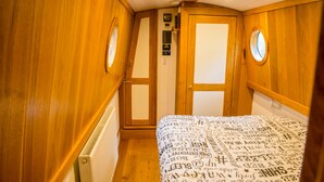 A wooden interior with a bed, a radiator, and a wall-mounted thermostat.