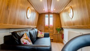 A cozy cabin interior with a leather sofa, wooden walls, and a small kitchenette.