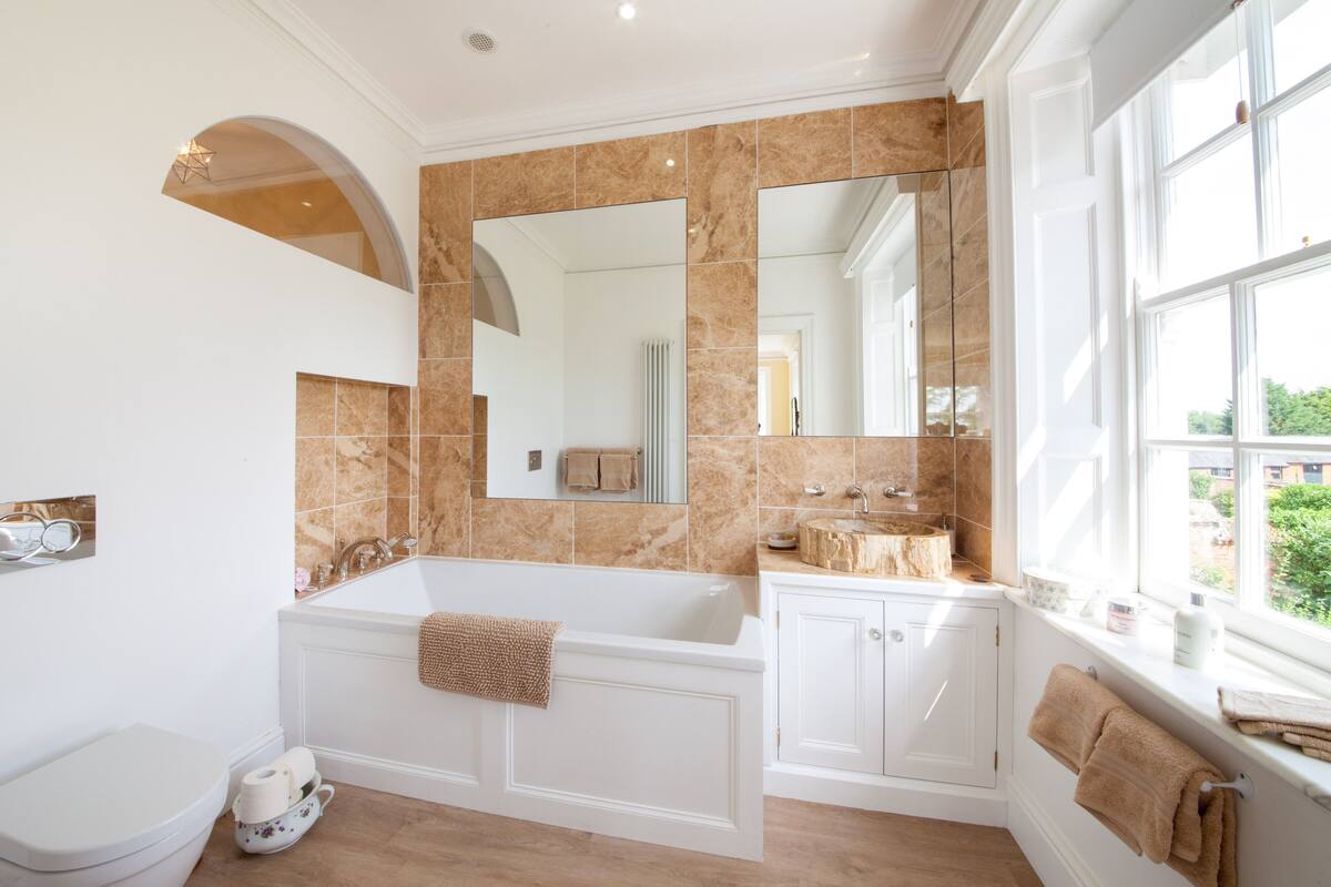A spacious bathroom with a large bathtub, a double sink vanity, and a large mirror.