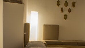 A neatly made bed with a pillow, a bedside table with a cup and saucer, and a book. - Casa Latina B&B (Naples)