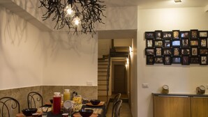 A dining area with a table set for four, a chandelier, and a wall of framed pictures. - Casa Latina B&B (Naples)