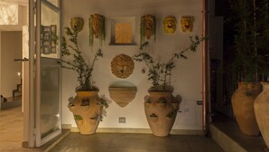 A building entrance with large terracotta planters, a wooden door, and a wall decorated with masks. - Casa Latina B&B (Naples)