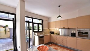 A modern kitchen with light wood cabinets, a granite countertop, and a built-in oven.