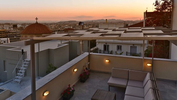 A rooftop terrace with a sofa, a table, and potted plants.