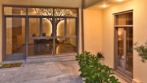 A modern building entrance with a glass door, a stone pathway, and a small garden area.