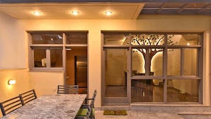 A dining area with a patterned table and chairs, a refrigerator, and a sliding glass door with a tree design.