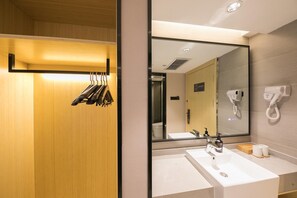 A modern bathroom with a wooden vanity, a large mirror, a sink, and a hairdryer mounted on the wall. - Piao Home Inn Beijing Guomao East (Beijing)