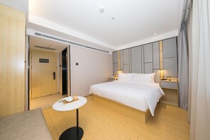 Ein Hotelzimmer mit einem Bett, einem Nachttisch und einem kleinen runden Tisch mit Teekanne und Tasse.