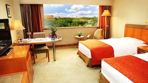 A hotel room with two beds, a desk, a chair, a TV, and a view of a cityscape. - Media Center Hotel - Beijing (BEIJING)