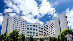 A multi-story hotel with a curved facade, a satellite dish on the roof, and a sign indicating it is a media center. - Media Center Hotel - Beijing (BEIJING)