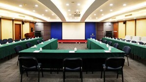 A conference room with long tables, chairs, and a large screen at the front. - Media Center Hotel - Beijing (BEIJING)