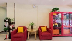 Une pièce avec deux canapés rouges, une petite table ronde, une bibliothèque et un buffet rouge aux portes vitrées.