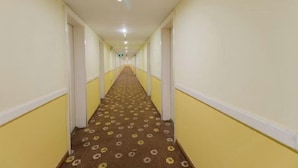 Un long couloir étroit aux murs jaunes et au tapis à motifs.