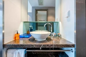 A modern bathroom with a large white vessel sink, a mirror, and a towel rack.