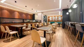 Interior de un restaurante moderno con suelo de madera, varias mesas y sillas.