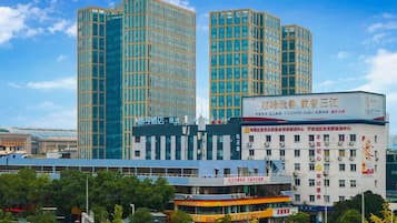 Un edificio moderno de varios pisos, con amplios ventanales y señalización que indica que es un hotel.