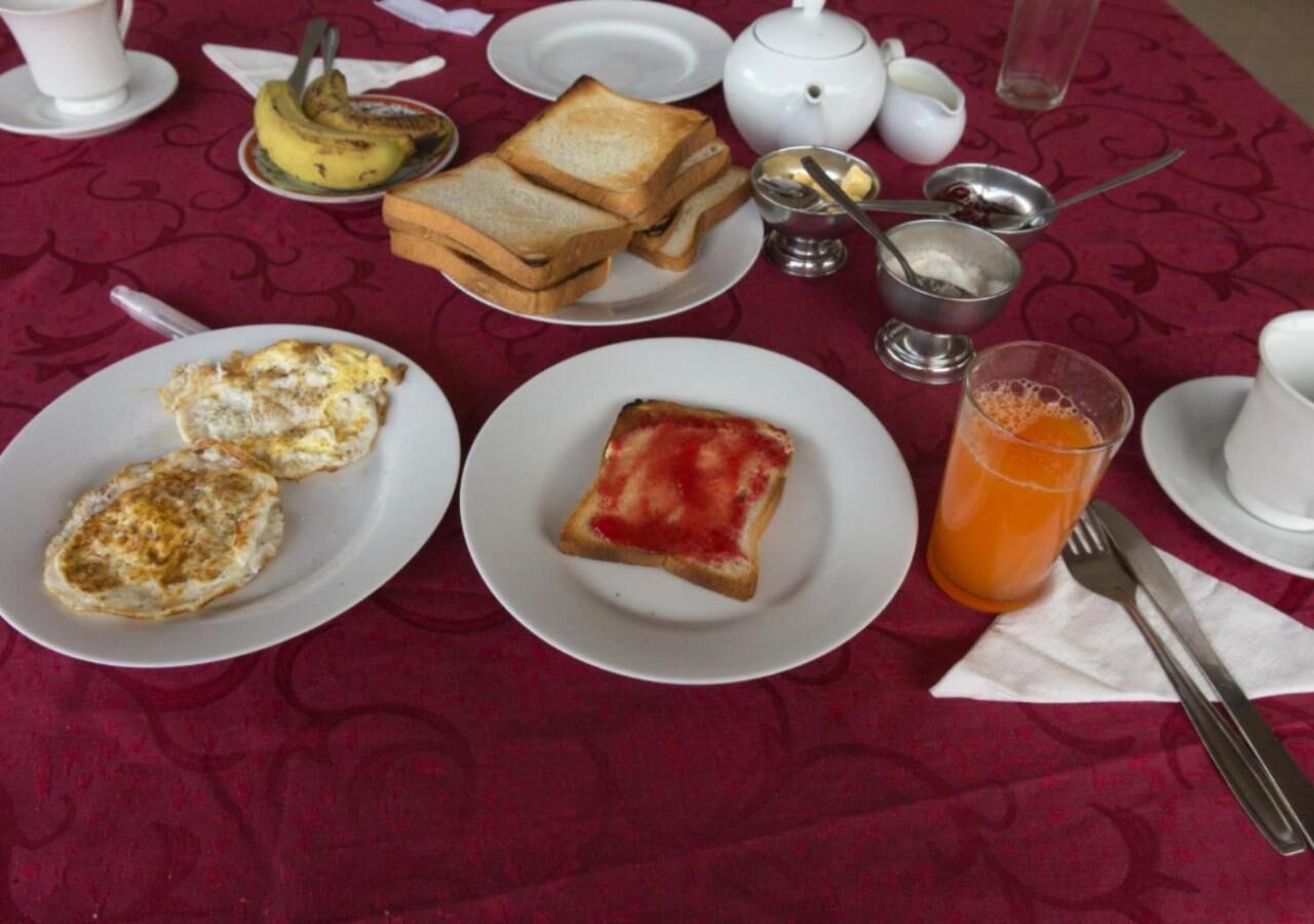 Taula preparada amb aliments per esmorzar, com ara torrades, ous i suc d'aranja.
