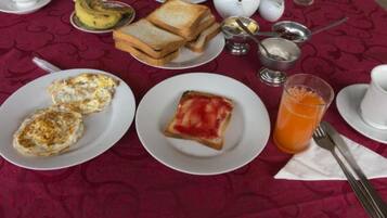 Taula preparada amb aliments per esmorzar, com ara torrades, ous i suc d'aranja.