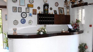 A reception area with a curved counter, a clock, and various framed items on the wall. - Anthoula Sun (Rhodes)