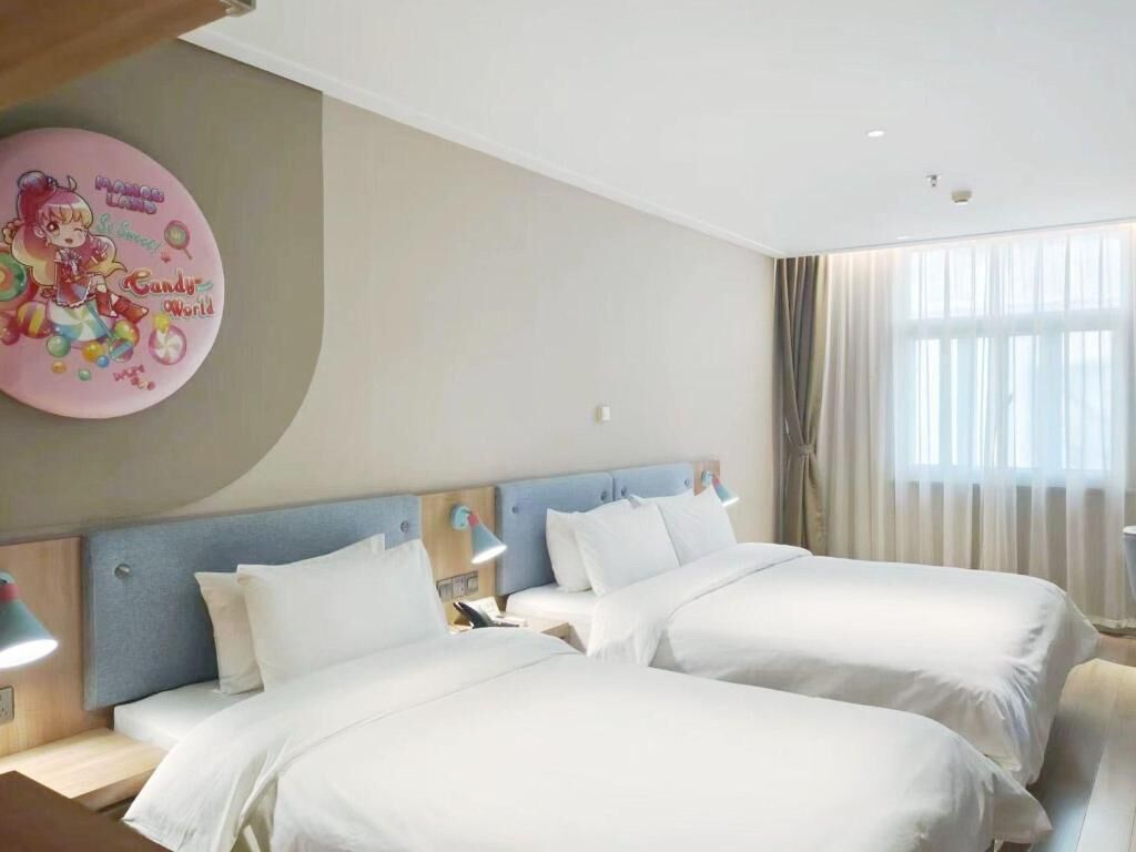A hotel room with two beds, a large wall clock, and a window with curtains.