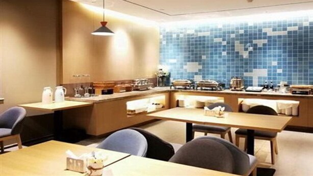 Eine moderne Küche mit blauer Mosaik-Spritzschutzwand, Holzschränken und einer zentralen Kochinsel mit Sitzgelegenheit.