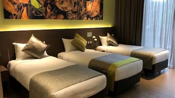 A hotel room with three beds, a large abstract painting on the wall, and a window with curtains.