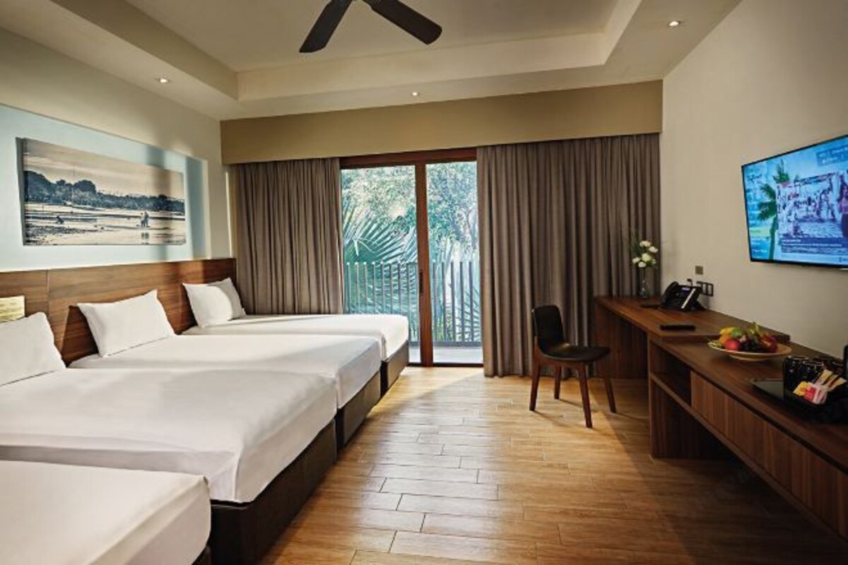 A hotel room with two beds, a desk with a chair, a TV, and a large window with curtains.