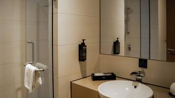Un baño moderno con cabina de ducha de vidrio, un lavabo blanco y un espejo grande.