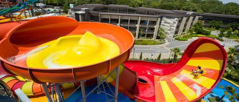 A water park with colorful slides and a building in the background.