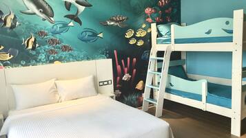 A room with a bed, bunk beds, and a mural of marine life.