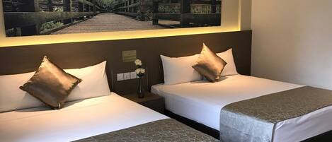 Two twin beds with white linens and brown pillows, a nightstand with a vase of flowers, and a framed picture above the beds.