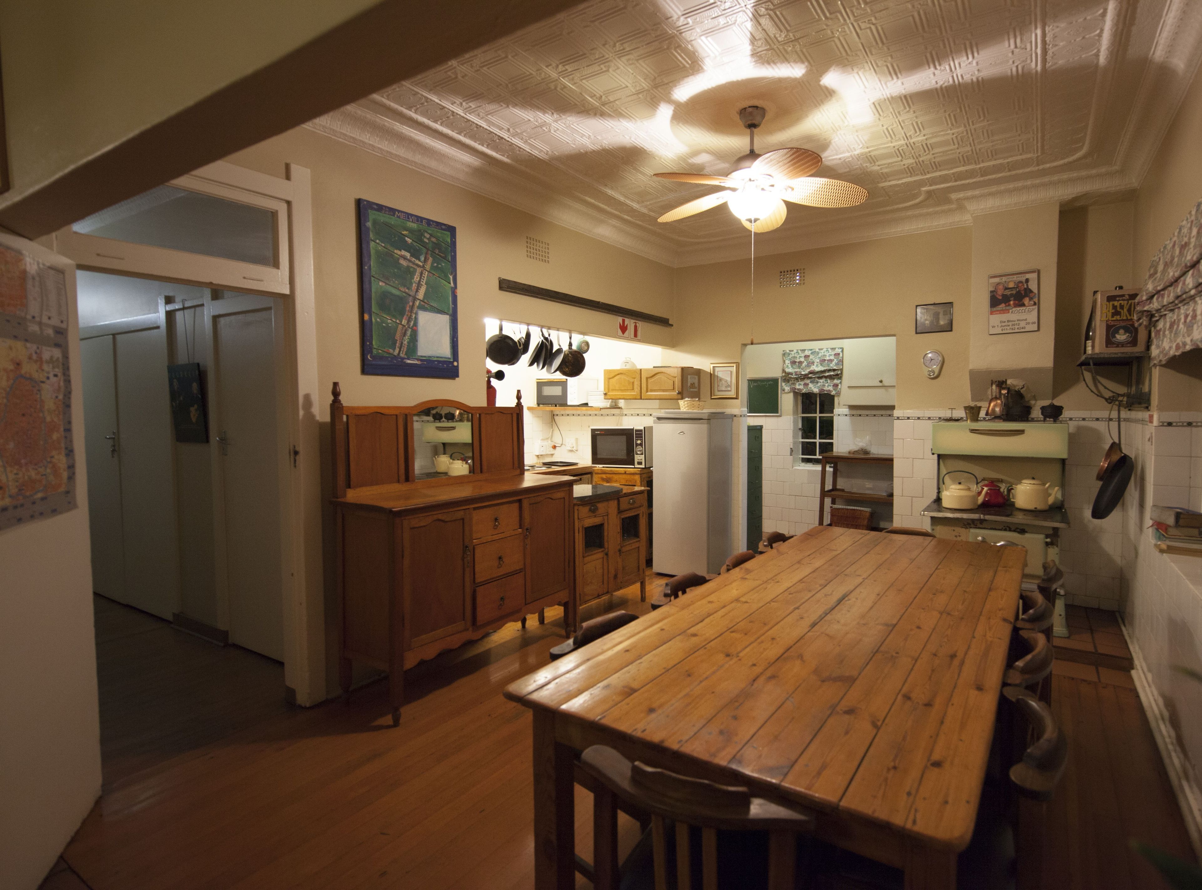 Une cuisine avec des meubles en bois, une table à manger et un ventilateur de plafond.