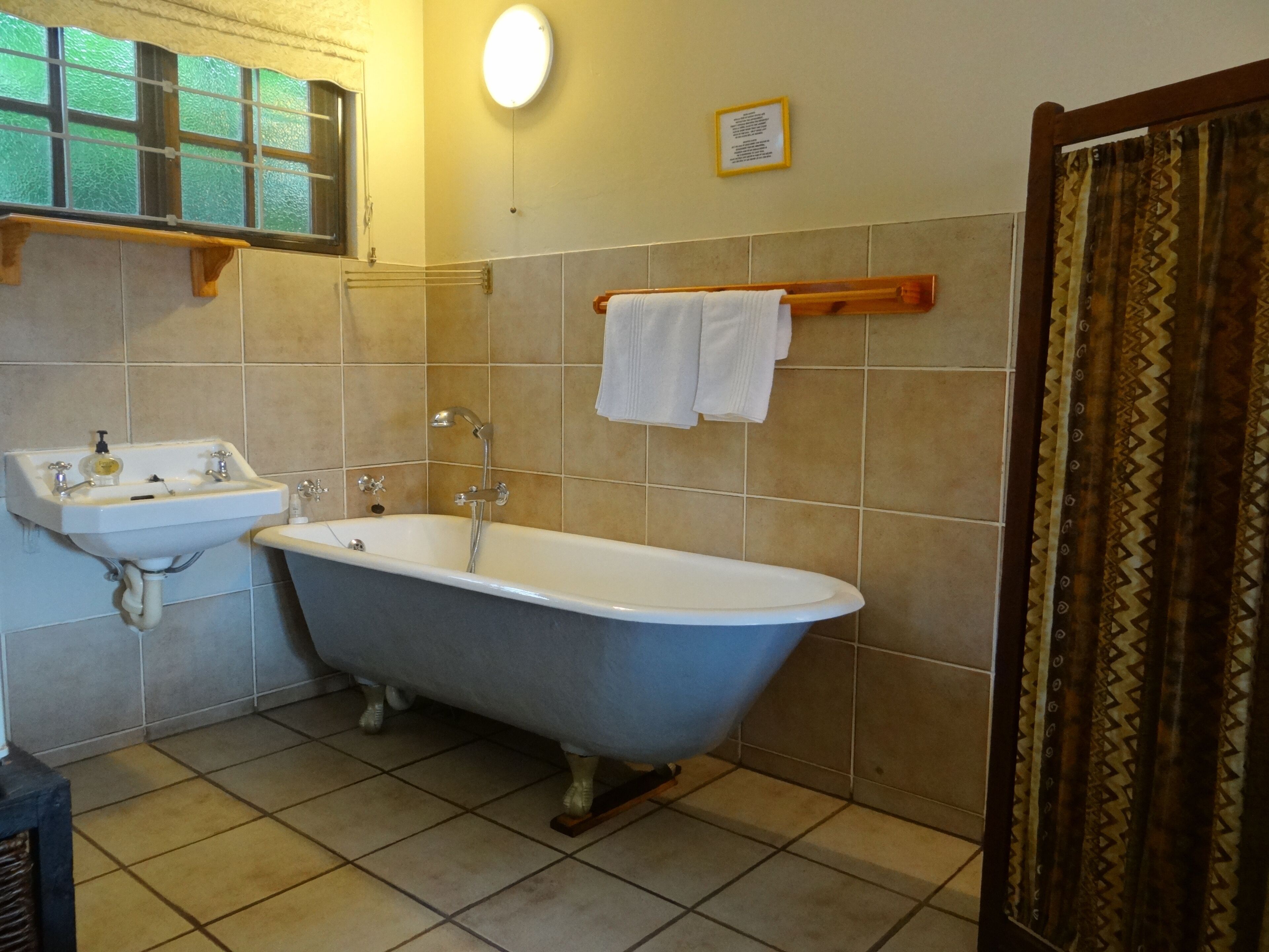 A bathroom with a freestanding bathtub, a sink, and a window with a view.
