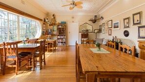 Un comedor con mesas y sillas de madera, un ventilador de techo y una estantería.