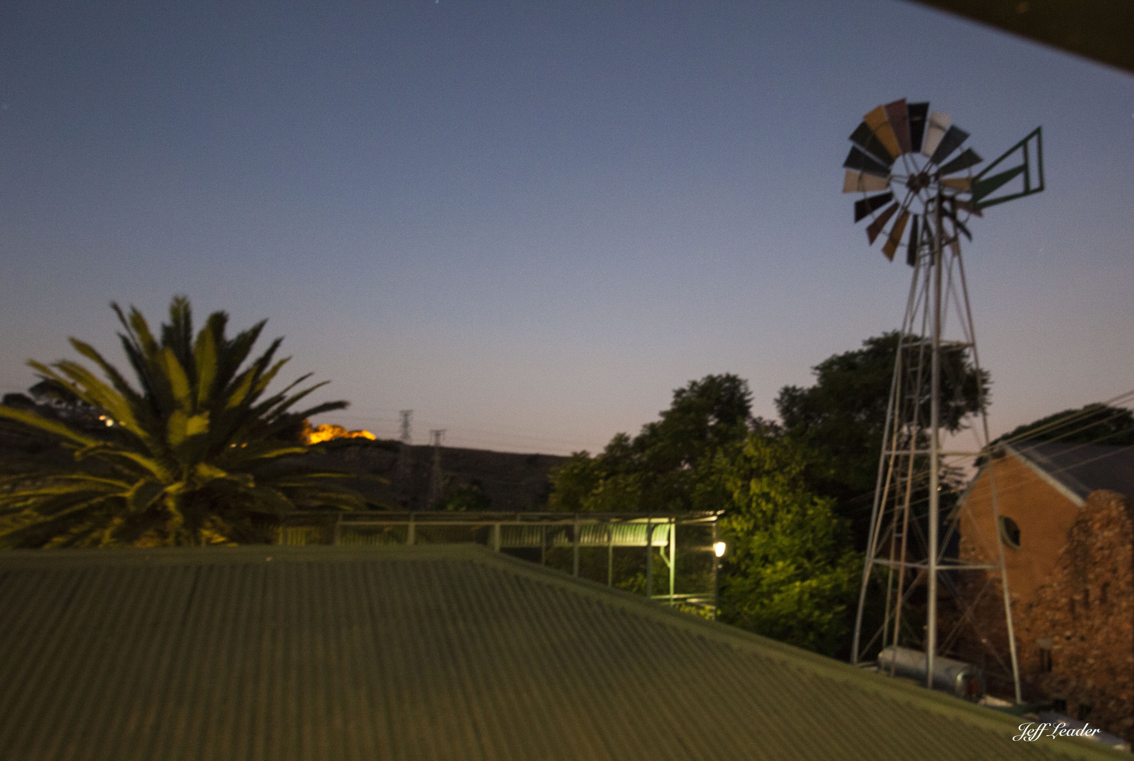A windmill on a rooftop with a metal roof and a building in the background.