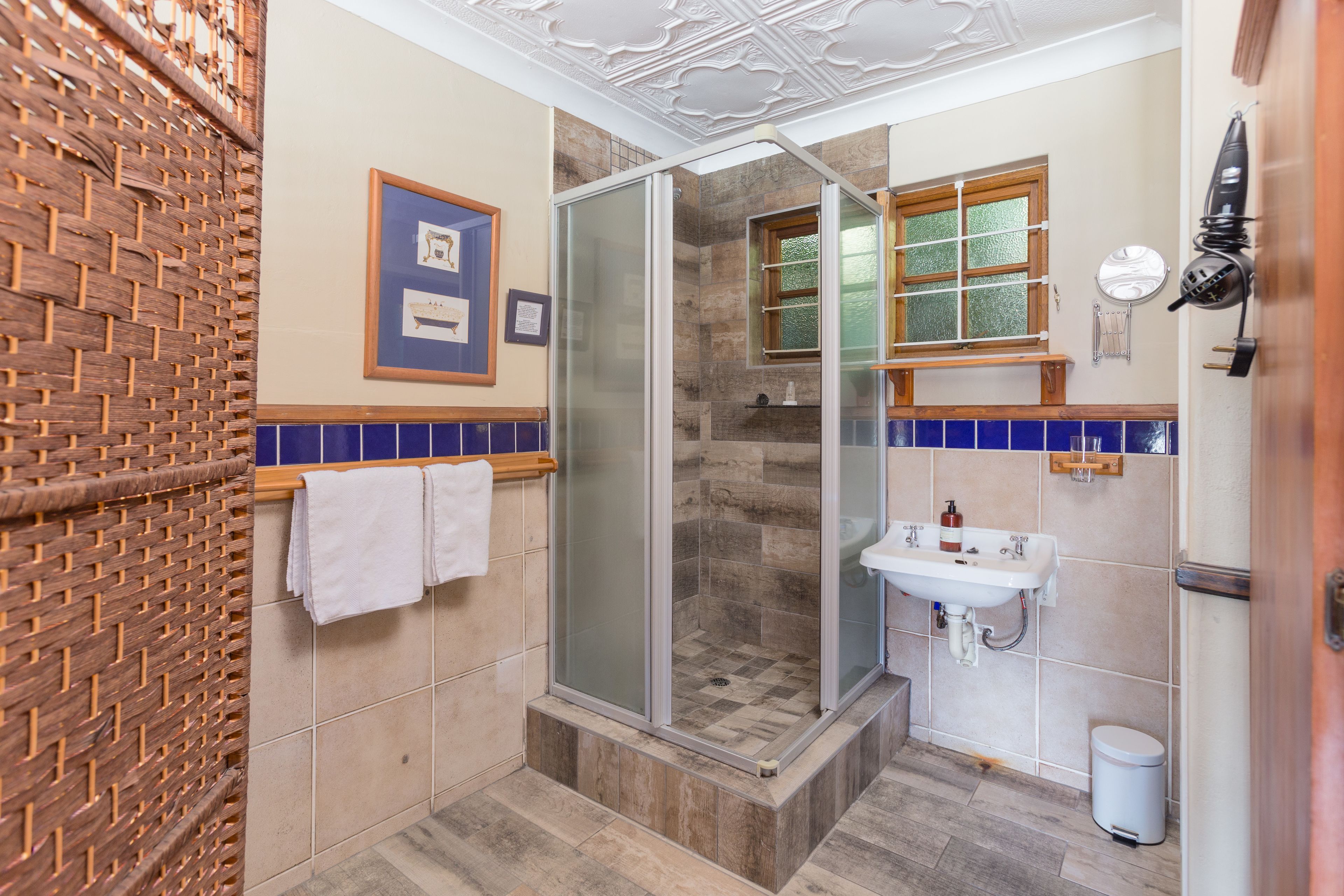 Une salle de bain avec une douche à parois de verre, un lavabo et un sol carrelé.