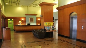 Eine Lobby mit Rezeption, Wartebereich mit Sesseln, Informationsschalter und Aufzug.