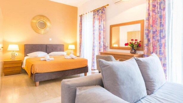 Et hotelværelse med en seng, et sengebord med lampe, et spejl og en stol.