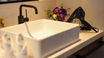 A white rectangular sink with a modern faucet, a small vase with flowers, and a hairdryer on the countertop.