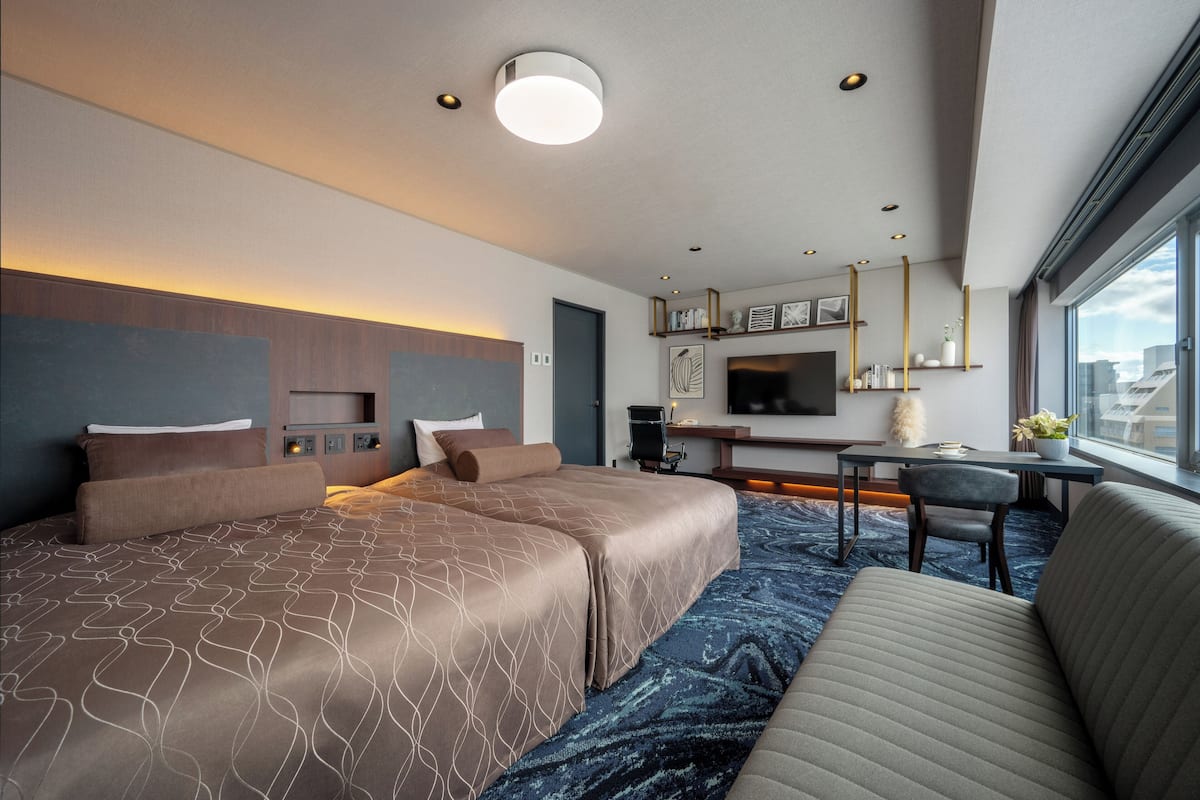 Ein modernes Hotelzimmer mit einem großen Bett, einer Couch, einem Schreibtisch und einem Fernseher.