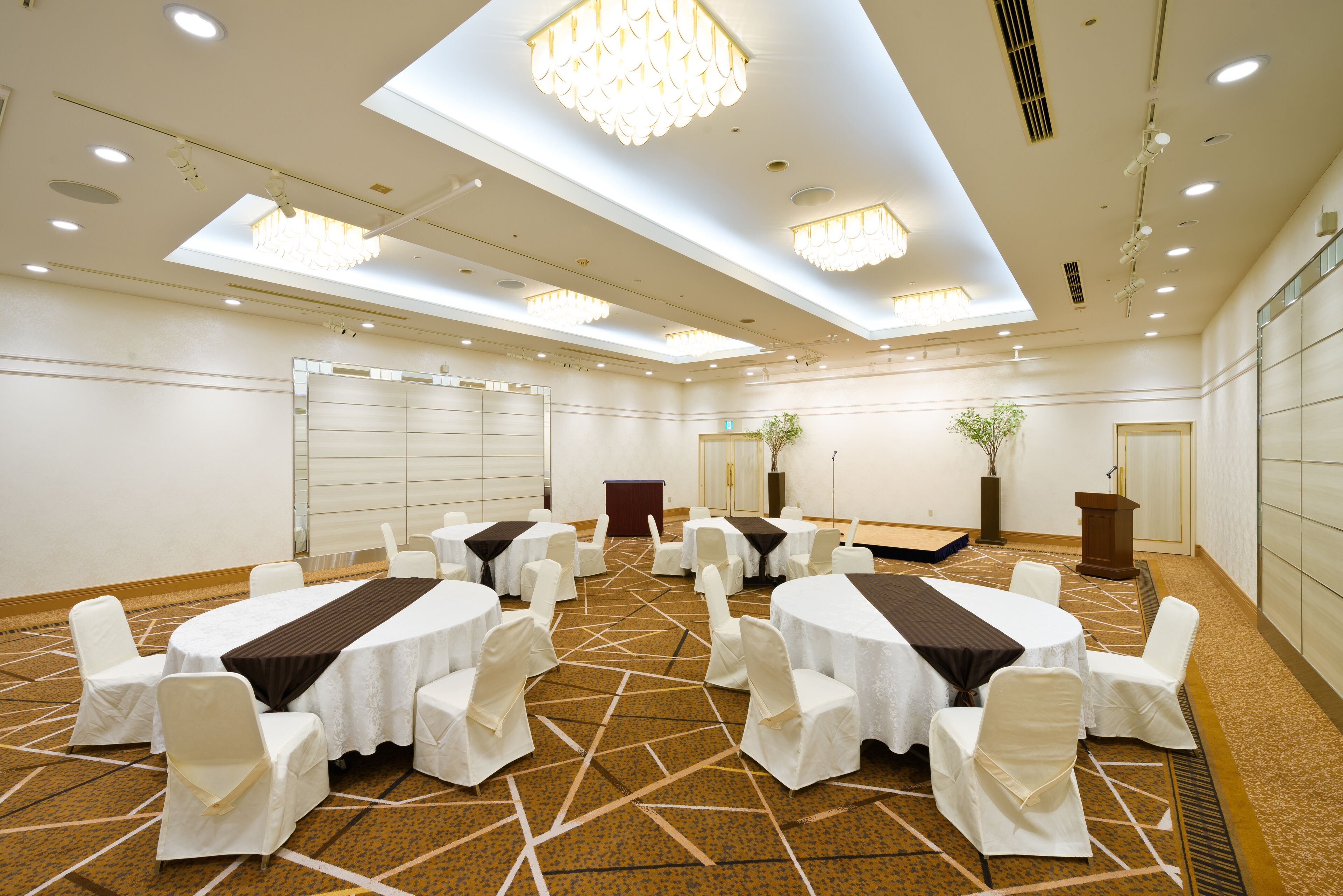 A conference room with round tables, white chairs, and a podium.