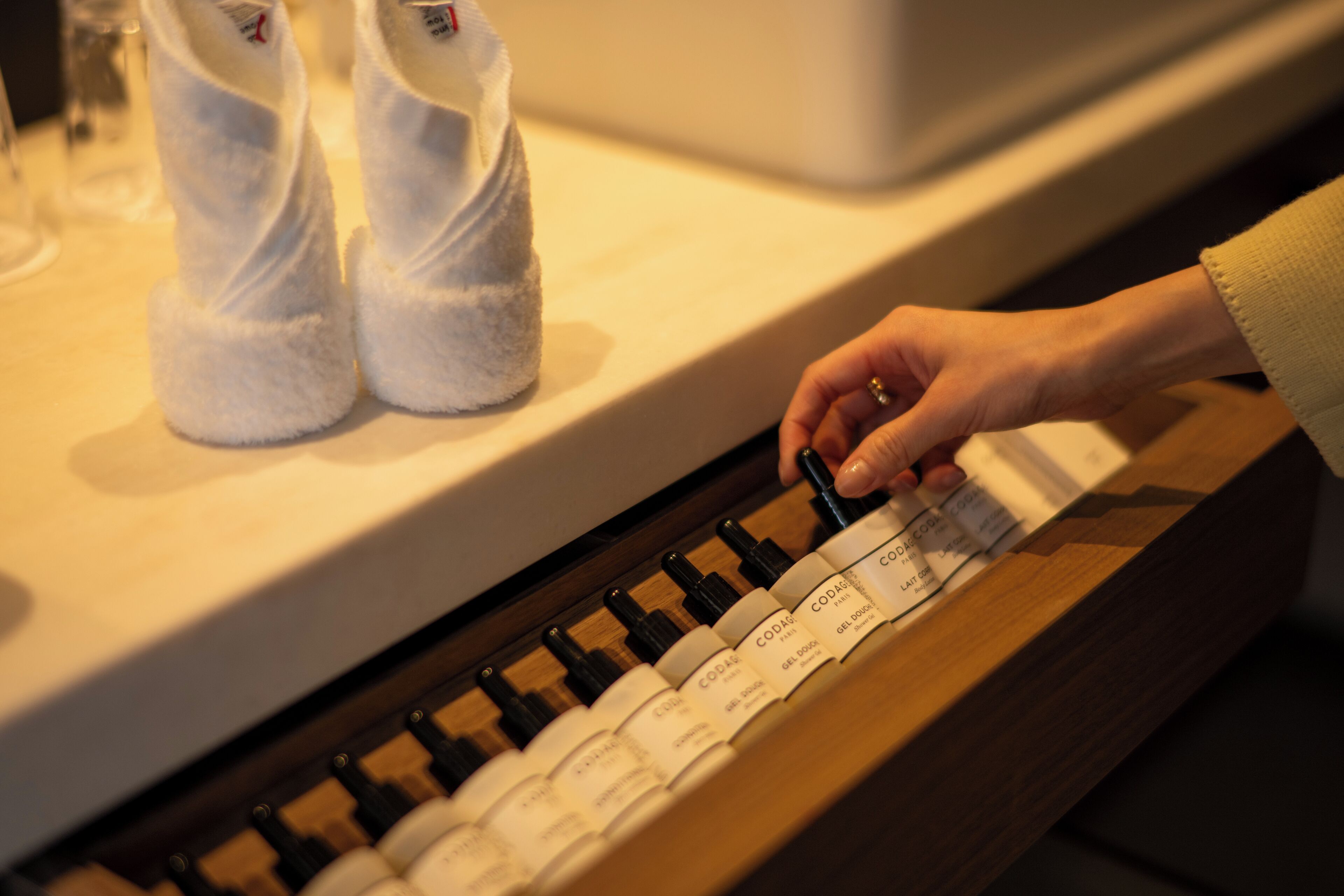 A hand selecting a bottle from a row of bottles on a counter.