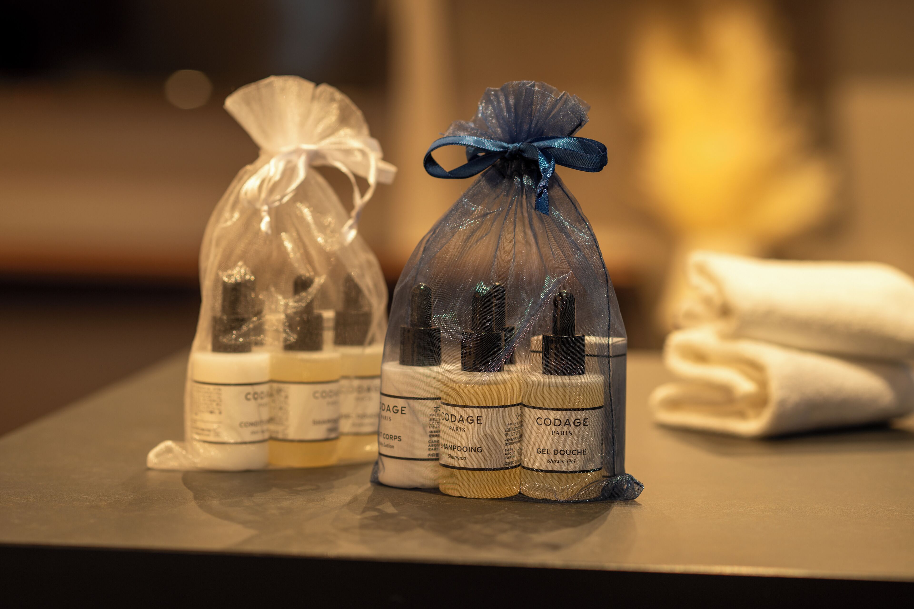 A bathroom counter with toiletries including bottles of Codage Paris shampoo and gel douche, and a towel.