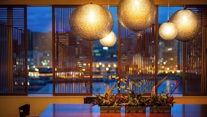 A dining area with a wooden table and chairs, a decorative plant centerpiece, and hanging spherical light fixtures. - Niigata Grand Hotel (Niigata)