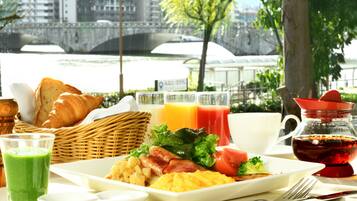 Una mesa de desayuno con cruasanes, huevos, tomates y jugo.