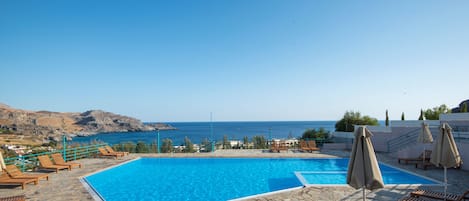 Una piscina al aire libre de temporada, sombrillas