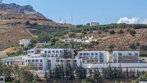 A hillside residential area with modern buildings, some with balconies, and a clear sky. - Sokol Resort (Agios Vasileios)