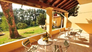 Eine Terrasse im Freien mit einem runden Tisch, Stühlen, einer Weinflasche und einem Glas.