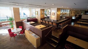A modern restaurant with a bar area, high tables, and booths. There are plants and a staircase leading to an upper level. - Yamagata Grand Hotel (Yamagata)