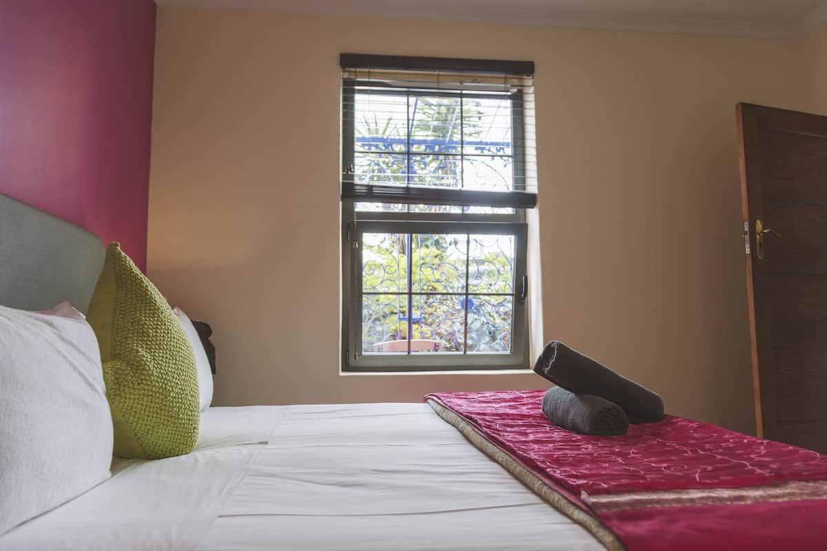 A bedroom with a bed, pillows, a window, and a door.